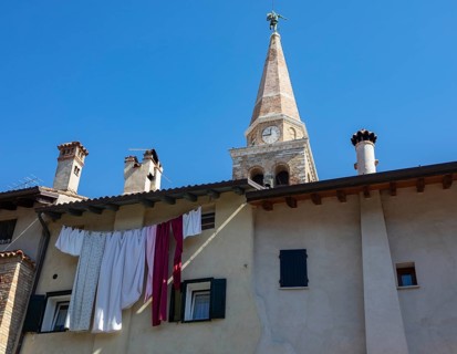 Laundry hanging to dry on a house facade with the Basilica of Sant Eufemia