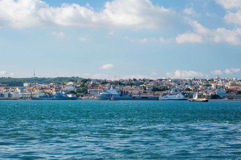 View of Tagus river with tourist boat and moored NATO warships in Lisbon