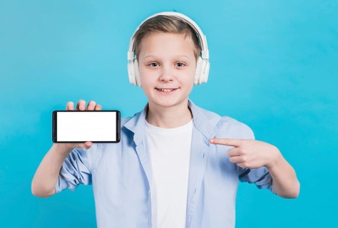 Close up boy wearing headphone head pointing her finger toward mobile phone with blank screen