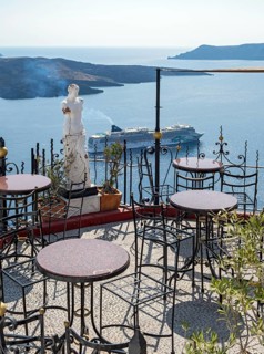 View of sea and cruise ship from terrace with chairs and table