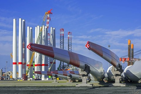 Wind turbine parts like huge rotor blades and steel tower sections for assembling wind turbines at REBO heavy load terminal in Ostend port