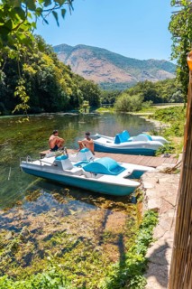 Two men sitting next to some pedalos in the river of The Blue Eye or Syri i kalter