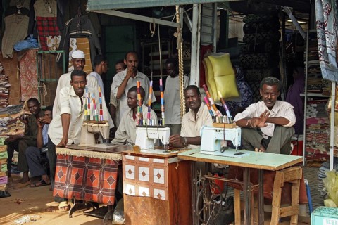 Men behind old treadle sewing machines in sewing workshop in Omdurman