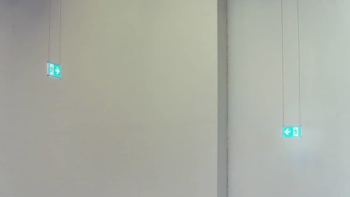Green emergency exit signs in front of white wall