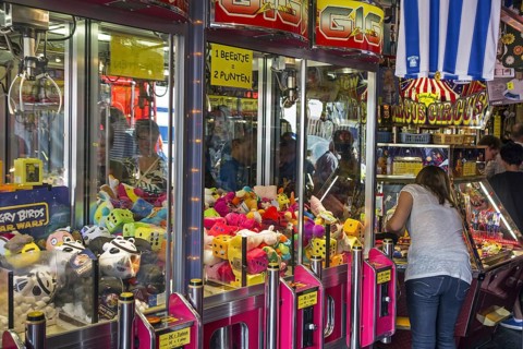 Arcade with claw crane game machines filled with toys and coin pusher