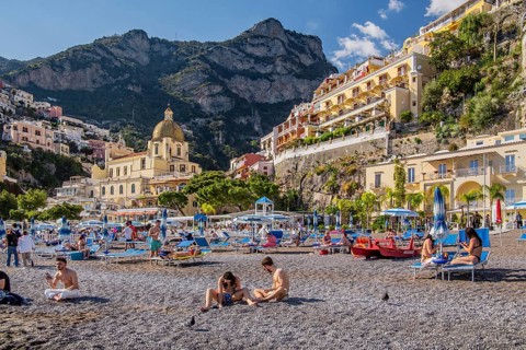 Beach with beach chairs and the church of Santa Maria Assunta