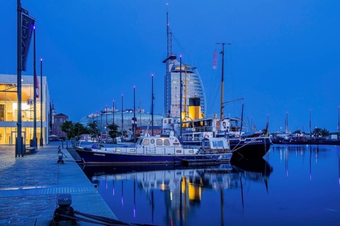 Historic ships in the New Harbour with the Atlantic Sail City Hotel at dusk