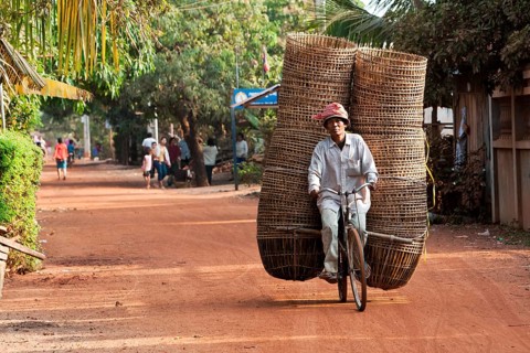 Man transporting many baskets on bicycle