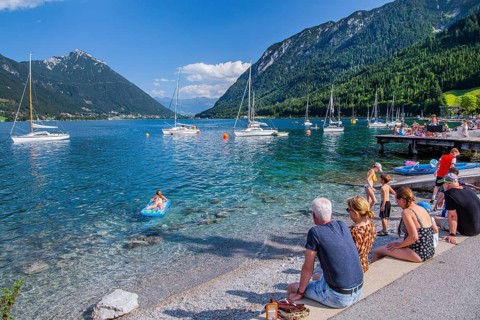 Holidaymakers on the lake promenade with sailing boats