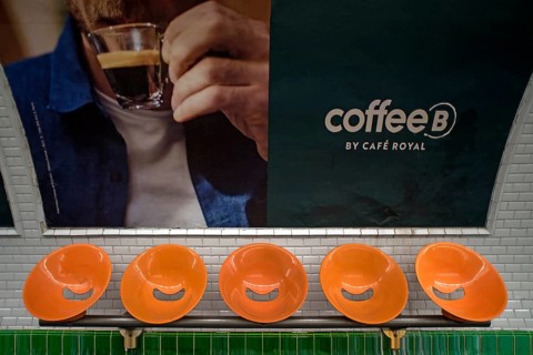 Orange seats in front of a large poster in the metro