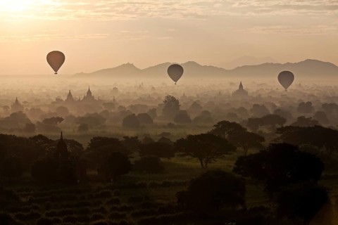 Hot air balloons over landscape with stupas