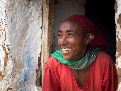 Laughing woman in front of a mud hut