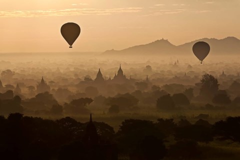 Hot air balloons over landscape with stupas