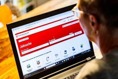 Woman with glasses looking for a job sits at home in front of her notebook and checks the internet site of the Federal Employment Agency for job offers