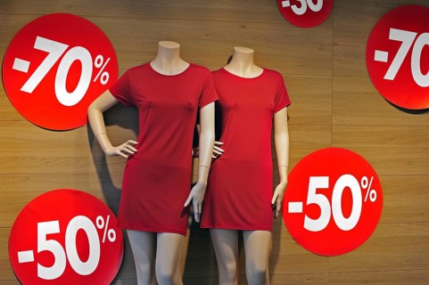 Discount notices showing deductions in shop window of clothes store during the summer sales in shopping street