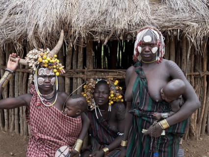 Women with small children in front of a hut