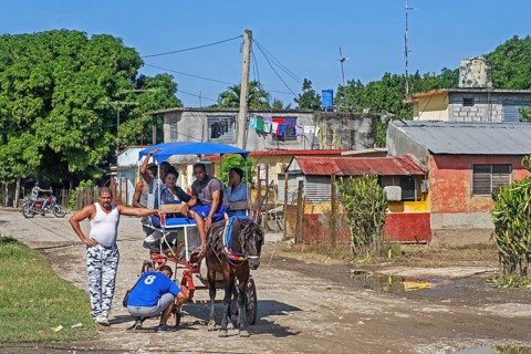 Cuban repairing horse-drawn taxi carriage in rural village in the Sierra Maestra