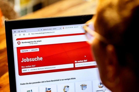 Woman with glasses looking for a job sits at home in front of her notebook and checks the internet site of the Federal Employment Agency for job offers