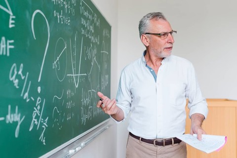Aged math teacher explaining formula classroom