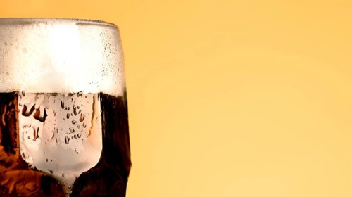 Cold glass beer yellow background