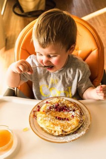 Cute little baby eating pancake plate high chair