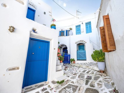 White Cycladic houses with blue doors and windows and flower pots