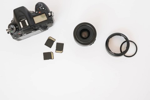Modern dslr camera memory cards camera lens with extension rings white backdrop