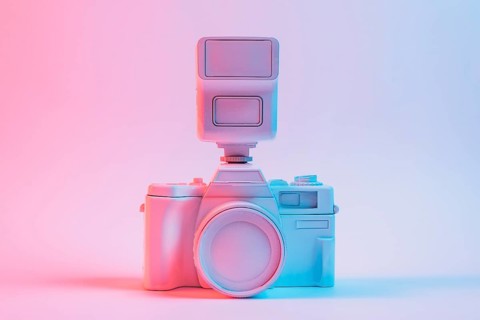 Blue light vintage painted pink camera against pink backdrop