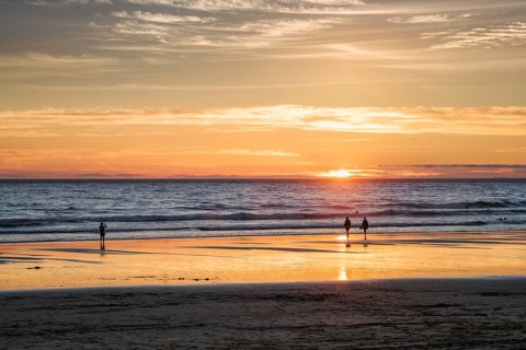 Atlantic ocean sunset with photographer silhouette taking images of surging waves at Fonte da Telha beach