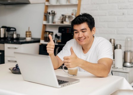 Man home during pandemic showing thumbs up during video call laptop