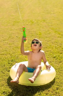 Boy with hat sunglasses playing with water gun