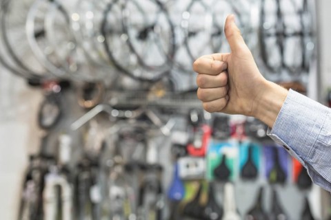 Male mechanic gesturing thumbs up bicycle workshop