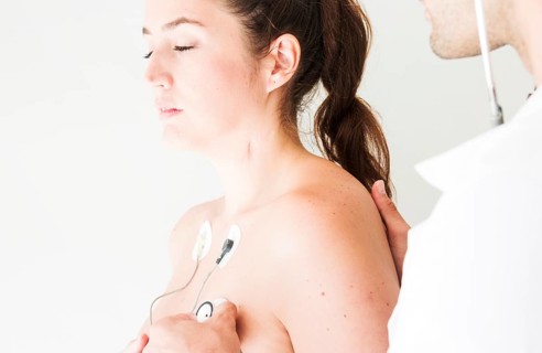 Doctor with stethoscope checking respiration lady
