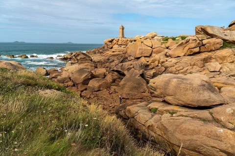 The rocks of the pink granite coast Cote de Granit Rose and the lighthouse Phare de Ploumanac'h near Ploumanac'h