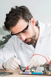 Technician examining computer motherboard with digital multimeter