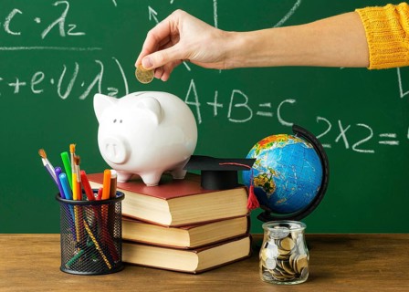 Person putting coins piggy bank with books pencils