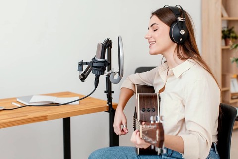 Side view female musician recording song while playing acoustic guitar home