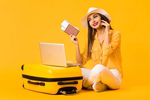Smiley woman posing luggage while holding plane tickets passport