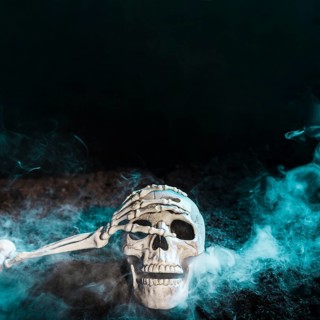 Skeleton s hand touching skull blue fog ground