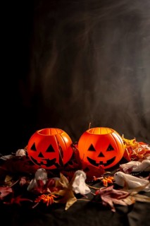 Halloween pumpkins on autumn leaves with smoke on a black background