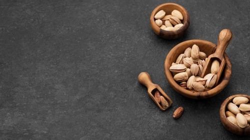 Pistachio nuts bowls with wooden spoons copy space