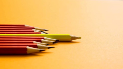 Yellow colored pencil lying red pencil against yellow background
