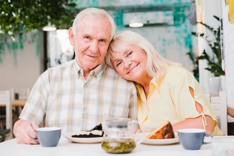Loving elderly couple drinking tea eating cake