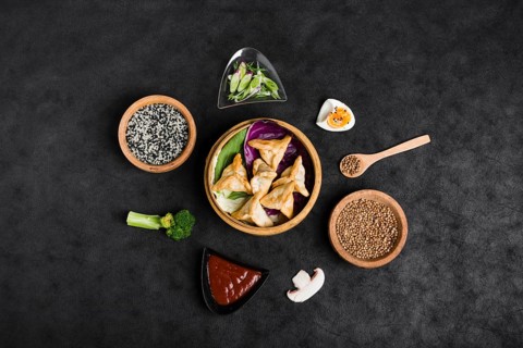 Top view dumplings steamers surrounded with sesame sauce coriander seeds broccoli mushroom black background