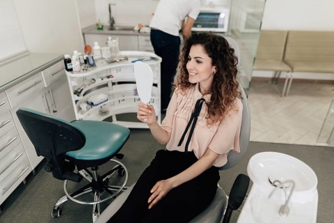 Woman looking teeth mirror dentist appointment