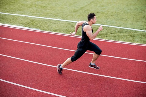 Male athlete arrives finish line racetrack during training session