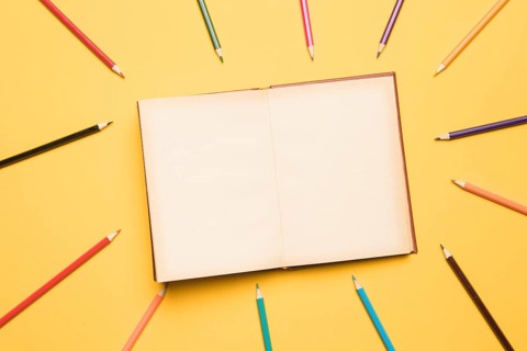 Open sketchbook surrounded by pencils different colors