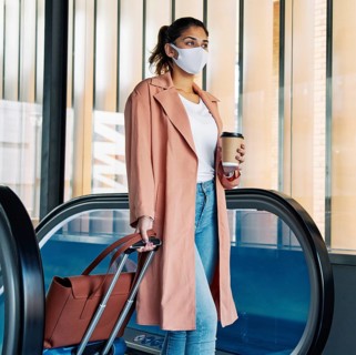 Woman with luggage medical mask airport during pandemic