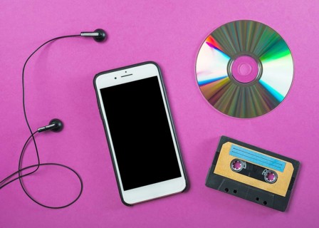 Earphone cellphone compact disc cassette tape purple background