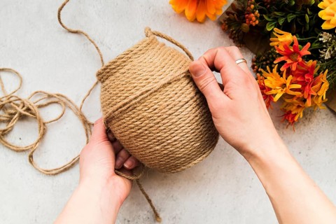 Overhead view woman making string with jute string textured backdrop